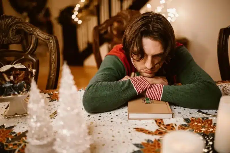 man sitting sad on a table for a article on decentering men during the holiday season